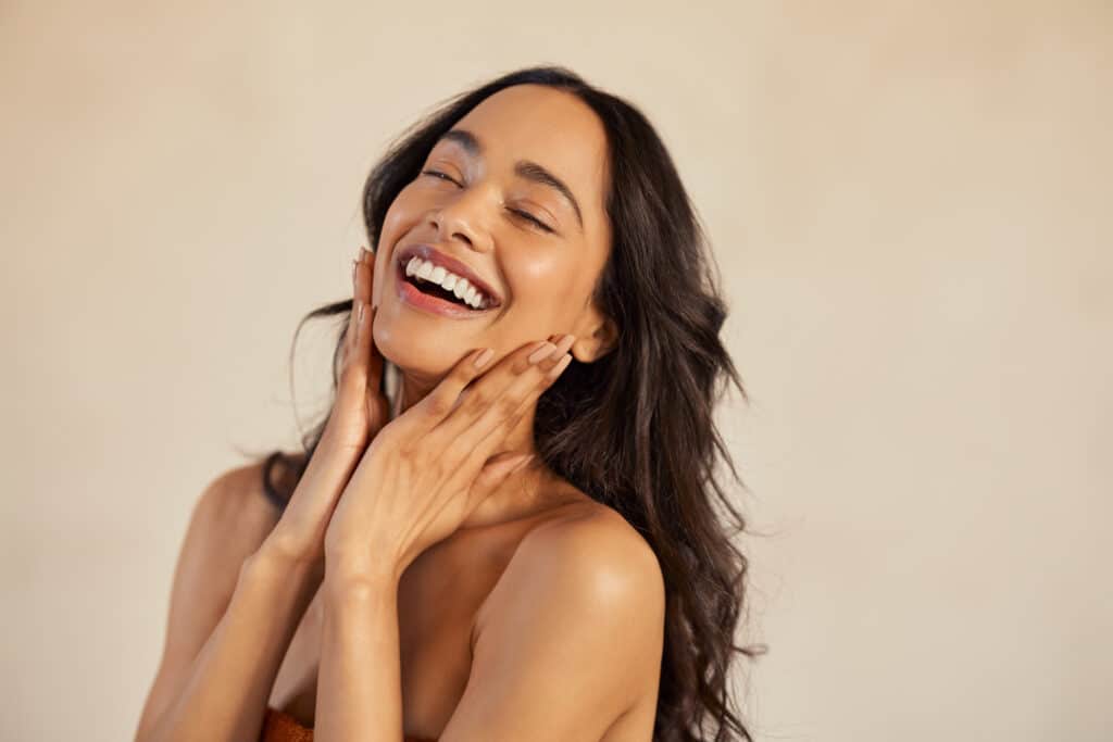 Beautiful laughing woman touching her skin